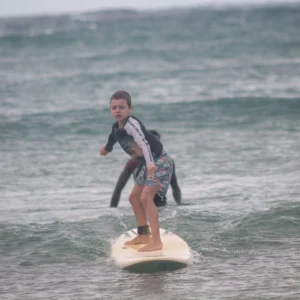 A young surfer rides a gentle wave at Tofo Beach, demonstrating their beginner surf skills during a lesson with Wutsita Surf School in Tofo, Mozambique.