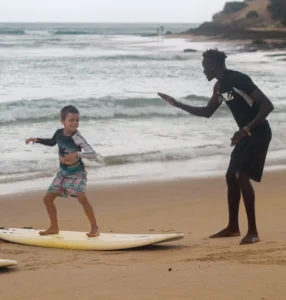 Wark, the surf instructor guides a young student in mastering their stance on the sand during a surf lesson at Tofo Beach, provided by Wutsita Surf School in Mozambique.